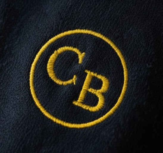 Close-up of a yellow 'CB' logo on a dark fabric background